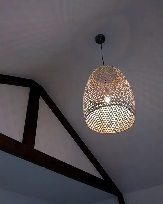 Rieten hanglamp onder een schuin dak met houten balken